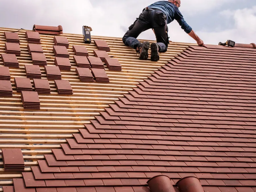 Roofer laying clay tiles on a house