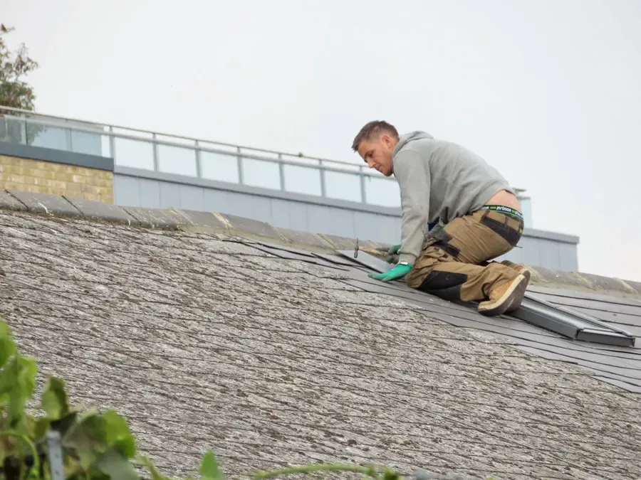 Worker installing roof shingles